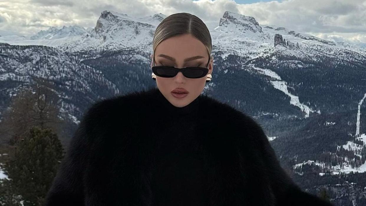 Influencer @romaneinnc wears a black fur coat, leather black gloves and oval sunglasses on holiday in the mountains