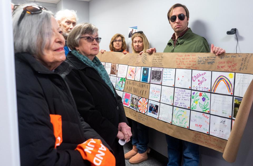 Connie Fewlass, of Warminster, second from left, alongside CeaseFirePA members and supporters hands over the signed and decorated banner to a staffer at Sen. Frank Farry's office after their vigil to remember gun violence victims and to mark 200 Days of Pennsylvania Senate inaction on bipartisan gun safety bills in Langhorne on Friday, Dec. 8, 2023.

[Daniella Heminghaus | Bucks County Courier Times]