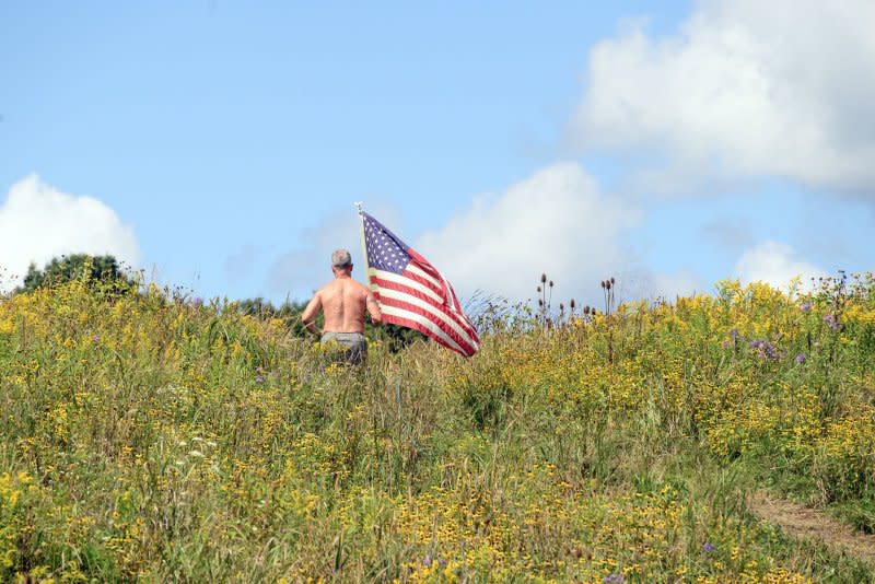 An unidentified visitor jogs pass the Wall of Names and up the hill through a field of wildflowers with an American flag after the public wreath-laying service at the Flight 93 National Memorial on Monday near Shanksville, Penn., on Monday. Photo by Archie Carpenter/UPI