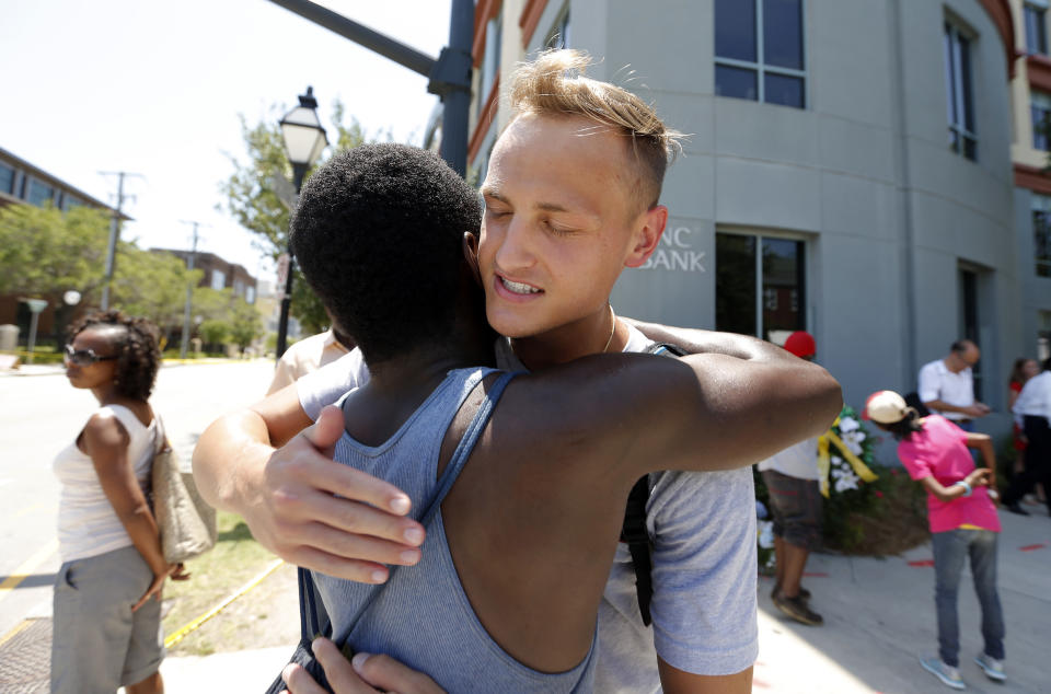 Tyler Francis, right, hugs Shondrey Dear after praying together, Thursday, June 18, 2015 at a make-shift memorial near the Emanuel AME Church following a shooting Wednesday night in Charleston, S.C. Shooting suspect Dylann Storm Roof, 21, was captured without resistance in North Carolina Thursday after an all-night manhunt, Charleston's police chief Greg Mullen said. 