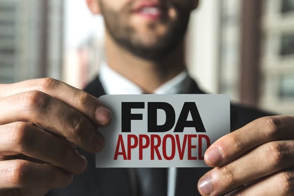 A businessman holding a card that reads, FDA Approved.