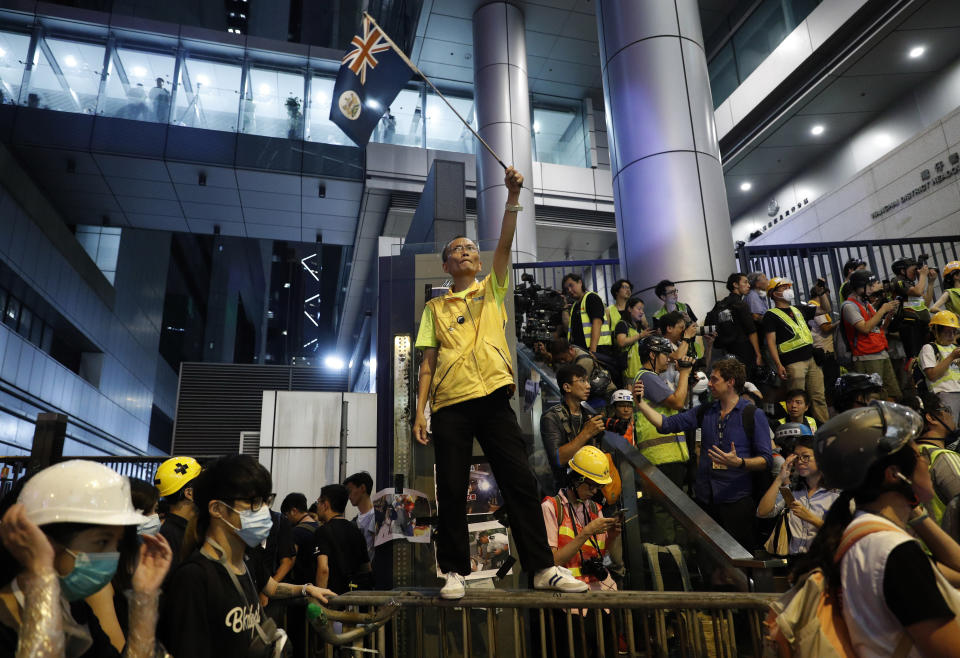 A protester waves a Hong Kong flag outside police headquarters in Hong Kong, Friday, June 21, 2019. More than 1,000 protesters blocked Hong Kong police headquarters into the evening Friday, while others took over major streets as the tumult over the city's future showed no signs of abating. (AP Photo/Vincent Yu)
