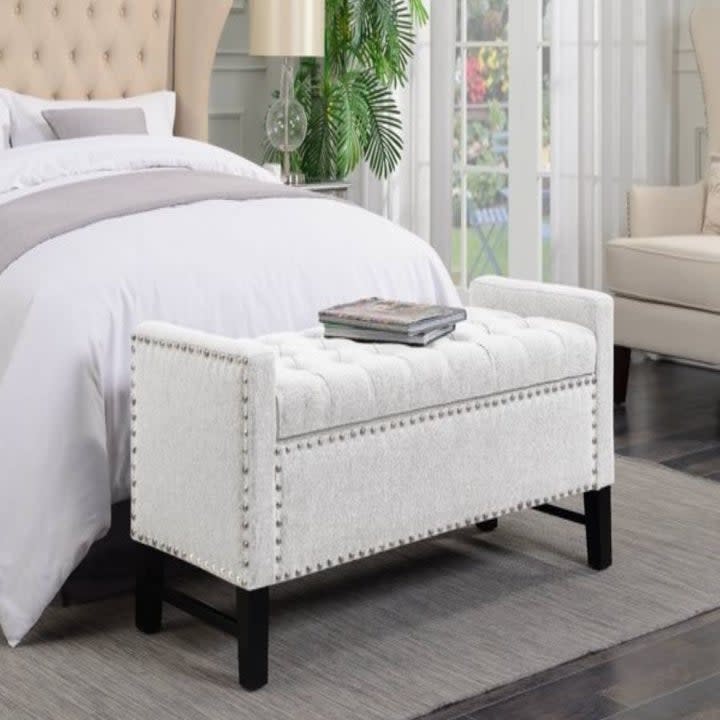 white nailhead bench at the foot of the bed