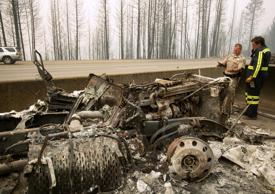 California Capt. Mark Loveless examines a scorched license plate on Interstate 5 as the Delta Fire burns in the Shasta-Trinity National Forest, Calif., on Thursday, Sept. 6, 2018. The highway remains closed to traffic in both directions as crews battle the blaze. (AP Photo/Noah Berger)