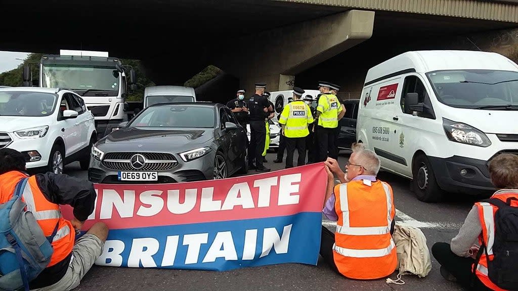 Police speaking to one another as protesters block an M25 junction on Monday (Insulate Britain/PA) (PA Media)