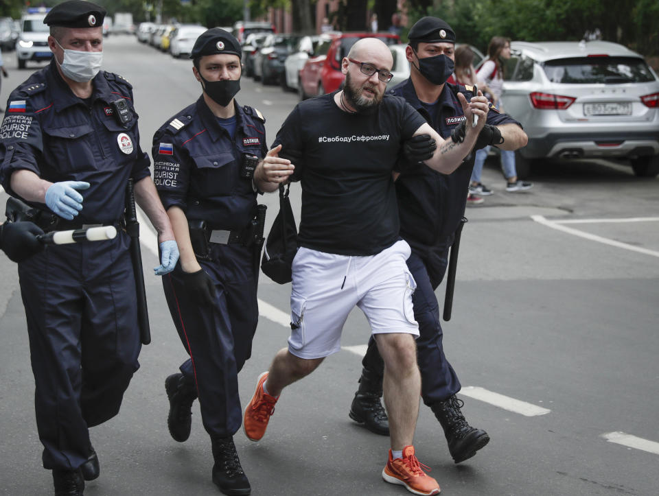 Police officers detain Alexander Chernykh, Kommersant newspaper journalist wearing a T-shirt with sign "Freedom to Safronov", during a rally to support Ivan Safronov near the Lefortovo prison in Moscow, Russia, Monday, July 13, 2020. Safronov, an ex-journalist who worked as an adviser to the director of Russia's state space corporation has been arrested and jailed on charges of passing military secrets to Czech intelligence. Ivan Safronov wrote about military and security issues before becoming an adviser to the head of Roscosmos. (AP Photo/Pavel Golovkin)