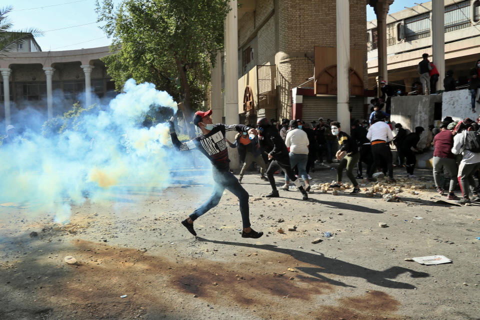 An anti-government protester throws throw back a tear gas canister fired by police during clashes in Baghdad, Iraq, Friday, Nov. 22, 2019. Iraq's massive anti-government protest movement erupted Oct. 1 and quickly escalated into calls to sweep aside Iraq's sectarian system. Protesters occupy several Baghdad squares and parts of three bridges in a standoff with security forces. (AP Photo/Hadi Mizban)