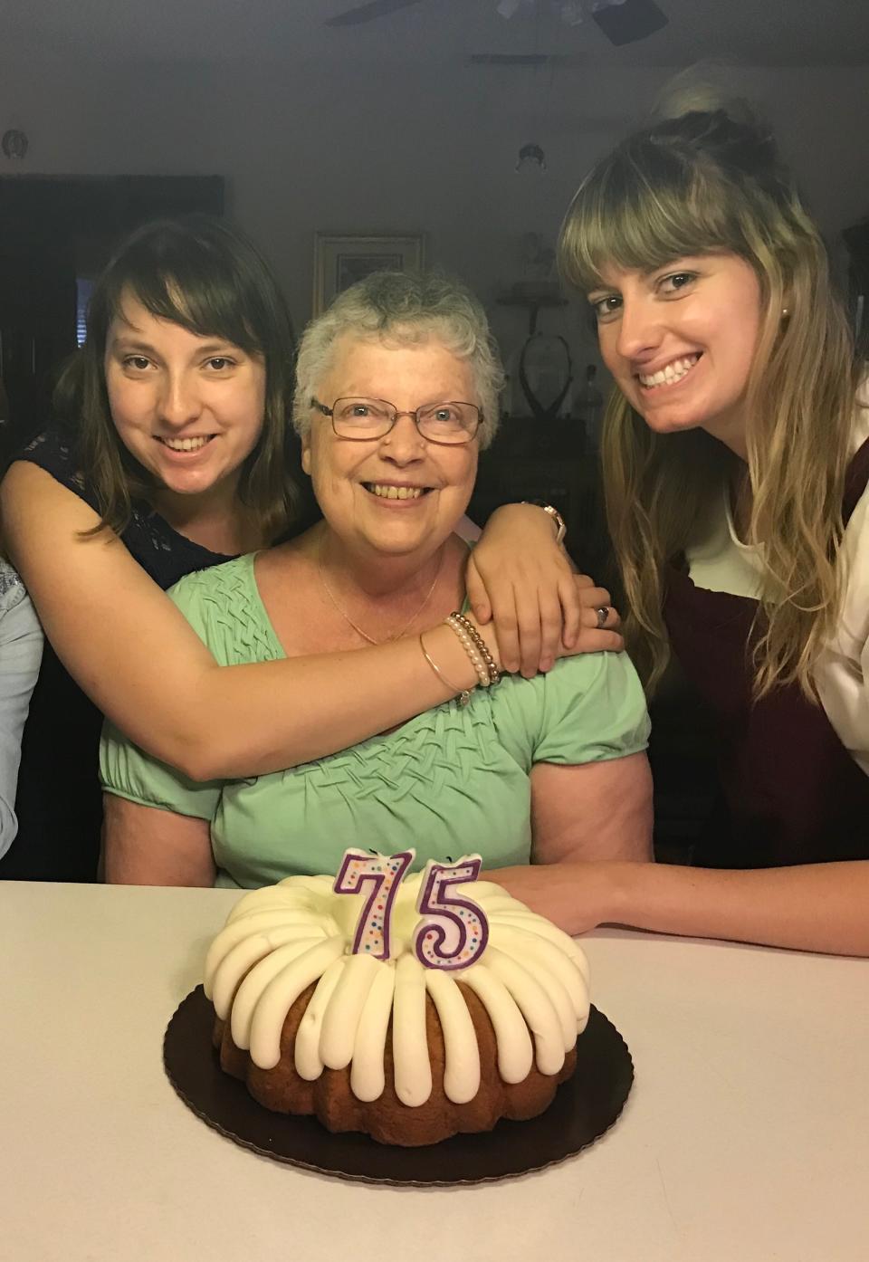 This June 3, 2018 photo shows Megan Hockman, from left, her grandmother Eleanor Raguse and sister Kayla Hockman posing with a birthday cake for Raguse in Fontana, Calif. The Hockmans plan a painting party with a remote brunch on Raguse’s lawn as she paints and munches from her porch on Mother’s Day. Isolation due to the coronavirus outbreak has led mothers and offspring to find creative ways to celebrate. (Lori Hockman via AP)