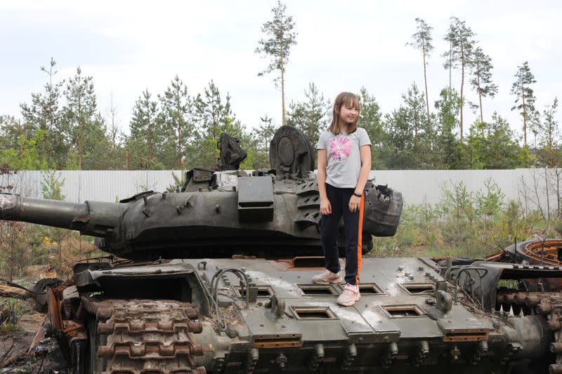 Girl stands on a destroyed Russian tank in the village of Dmytivka