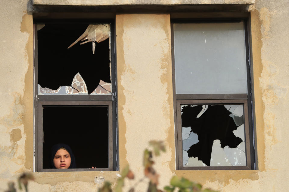 A Lebanese girl looks through a shattered glass window after Israeli shelling landed near her house, in Dahaira village, South Lebanon, Monday, Oct. 9, 2023. Israeli troops shot and killed several gunmen who crossed into the country from Lebanon, the Israeli Defense Forces said without specifying the number of people killed nor their alleged affiliation. (AP Photo/Mohammed Zaatari)