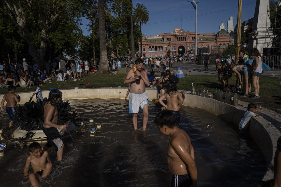 Soccer fans wade in water fountain after waiting for hours for a homecoming parade for the players who won the World Cup title, in Buenos Aires, Argentina, Tuesday, Dec. 20, 2022. A parade to celebrate the Argentine World Cup champions was abruptly cut short Tuesday as millions of people poured onto thoroughfares, highways and overpasses in a chaotic attempt to catch a glimpse of the national team. (AP Photo/Rodrigo Abd)