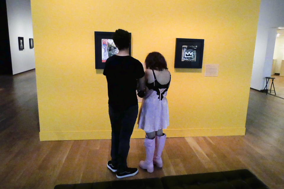 Visitantes observan pinturas atribuidas a Jean-Michel Basquiat en el Museo de Arte de Orlando el miércoles 1 de junio de 2022, en Orlando, Florida. El viernes 24 de junio el FBI hizo una redada en el museo y confiscó más de 20 supuestas obras de Basquiat por dudas sobre su autenticidad. (Foto AP/John Raoux)