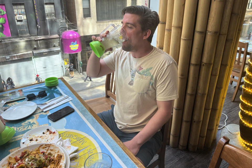 Matt Urben drinks a margarita at the Margaritaville restaurant in New York's Times Square on Saturday, Sept. 2, 2023, following news of the death of Jimmy Buffett. Urben says he's attended about 48 of Buffett's concerts over the years. (AP Photo/Bobby Caina Calvan)