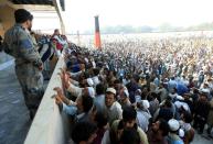 Afghan men wait to receive tokens needed to apply for the Pakistan visa, after people were killed in a stampede in Jalalabad