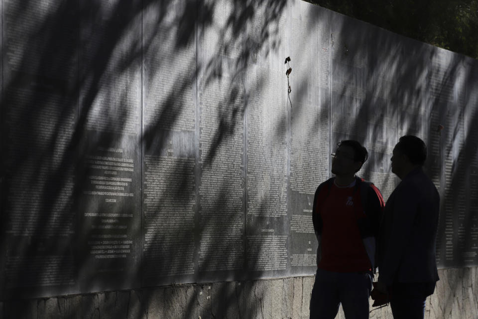Dos personas que asisten a una manifestación antigubernamental observan los nombres de 30.000 víctimas de la guerra civil en el Monumento a la Memoria y la Verdad en San Salvador, El Salvador, el 15 de enero de 2023. La marcha conmemoró el 31er aniversario de la firma de los acuerdos de paz que pusieron fin al conflicto (1980-1992). (AP Foto/Salvador Meléndez)