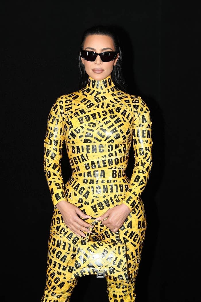 Kim holds her purse while wearing the caution tape dress