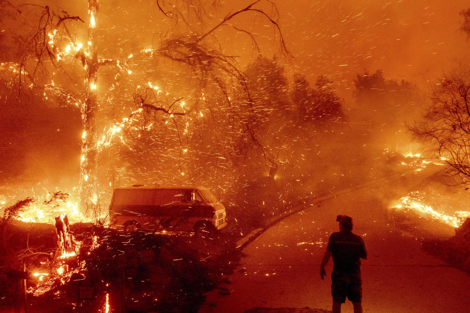 FILE - Bruce McDougal watches embers fly over his property as the Bond Fire burns through the Silverado community in Orange County, Calif., Dec. 3, 2020. A Southern California county has filed lawsuits alleging the electric utility's negligence caused two wildfires that collectively burned thousands of acres, prompting the evacuation of tens of thousands of people. (AP Photo/Noah Berger, File)