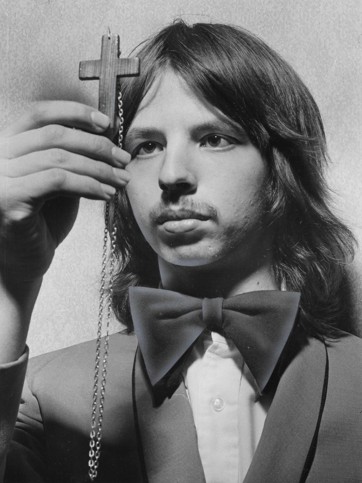 Summit Mall Theater usher Doug Isenhart inspects the wooden cross that he wore around his neck during the first screenings of “The Exorcist” in February 1974.