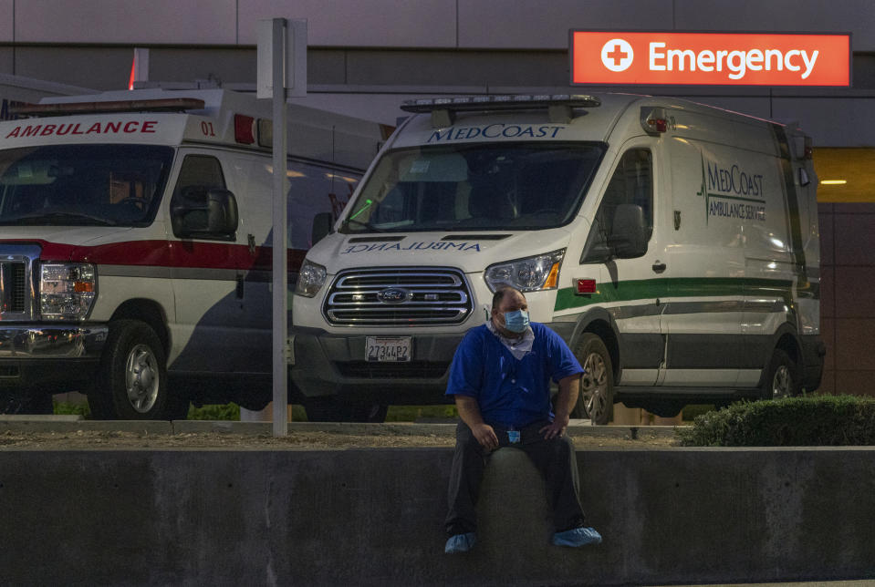 Darren Arthur, an environmental services worker, takes a break outside the Los Angeles County+USC Medical Center emergency ramp in Los Angeles, late Wednesday, Dec. 16, 2020. The state has been grappling with soaring cases and hospitalizations. Hospitals are filling up so fast that officials are rolling out mobile field facilities and scrambling to hire more doctors and nurses. (AP Photo/Damian Dovarganes)