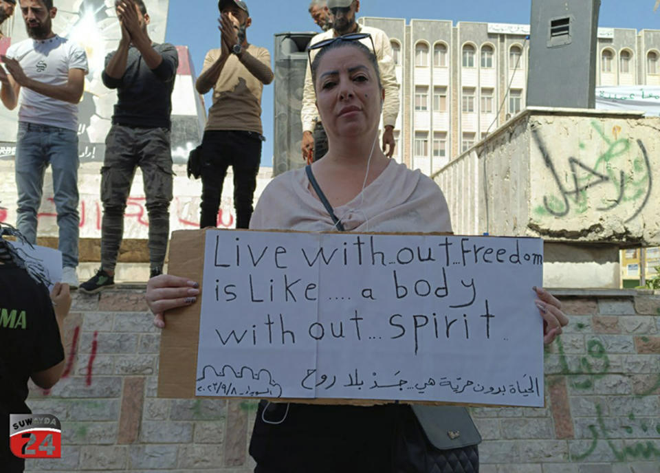 In this photo released by Suwayda24, a protester holds a placard during a demonstration in the southern city of Sweida, Syria, Friday, Sept. 8, 2023. The protests in the Druze-majority city have been ongoing for more then two weeks, initially driven by surging inflation and the war-torn country's spiraling economy but later widening to calls for the fall of the Assad government. (Suwayda24 via AP)