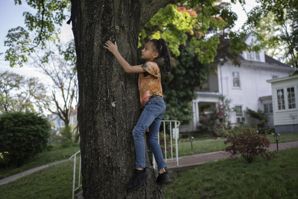 Caydence Manson climbs a tree while playing in her relative's front yard after school in Hartford, Conn., on Wednesday, May 25, 2022. Research and experts say many of the same racist factors that afflict Black peoples' health from cradle to grave - including redlining, discriminatory housing practices, lack of access to health care and environmental toxic exposures - are significant drivers of asthma, which both she and her brother have. (AP Photo/Wong Maye-E)