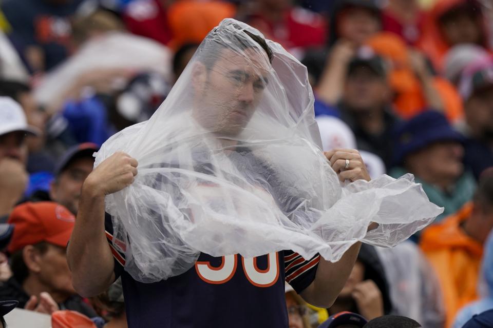A fan tries to stay dry during the first half of an NFL football game between the Chicago Bears and the San Francisco 49ers Sunday, Sept. 11, 2022, in Chicago. (AP Photo/Nam Y. Huh)