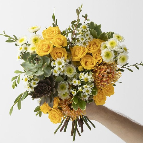 arm holding out yellow and white bouquet of flowers