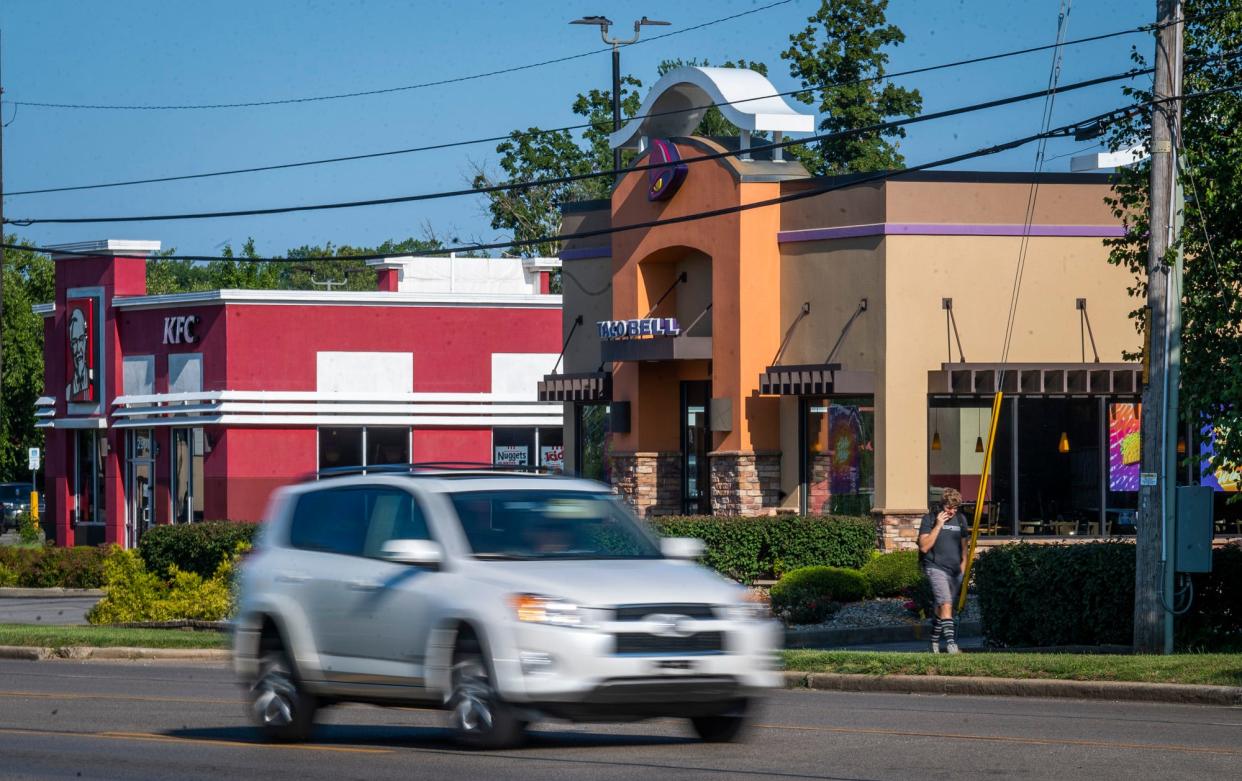 A man on the phone walks past the Taco Bell on Third Street on Friday, Aug. 18, 2023. The Taco Bell and KFC may soon be replaced with a Crew Carwash.