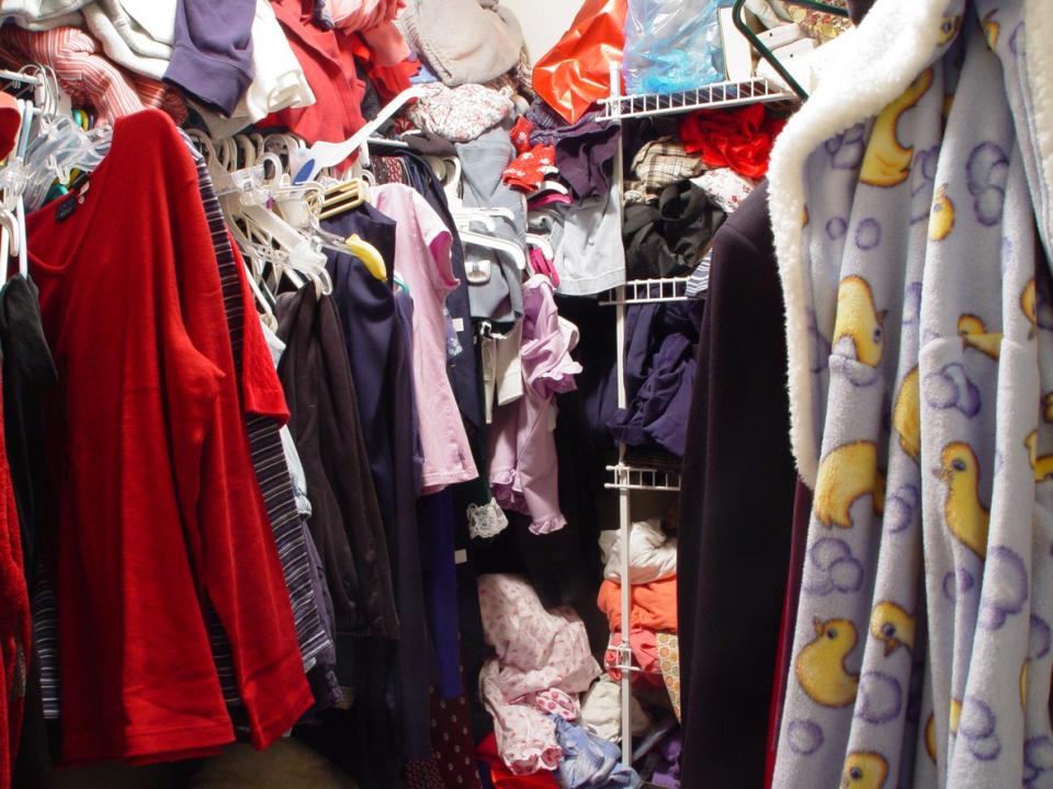 Clothes on hangers, shelves, and just stuffed into any available space in a closet