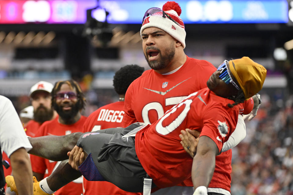 AFC defensive tackle Cameron Heyward of the Pittsburgh Steelers carries AFC wide receiver Tyreek Hill of the Miami Dolphins during the flag football event at the NFL Pro Bowl against the NFC, Sunday, Feb. 5, 2023, in Las Vegas. (AP Photo/David Becker)