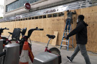 A pedestrian passes work being done to board up a Pret A Manger restaurant along K Street, Friday, Oct. 30, 2020, ahead of the presidential election, in downtown Washington not far from the White House. (AP Photo/Jacquelyn Martin)