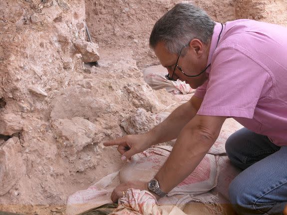 Jean-Jacques Hublin points to a crushed human skull, whose orbits are visible just beyond his finger tip.