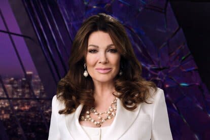 Lisa Vanderpump wearing a white pantsuit while in a purple room overlooking LA.