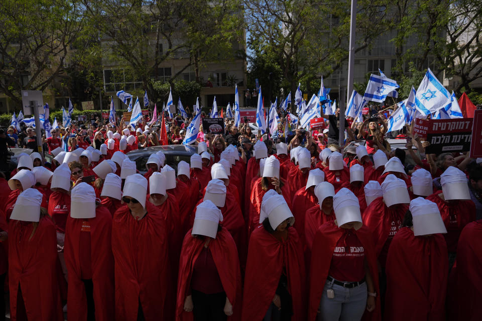 Israeli women's rights activists dressed as characters in the popular television series, "The Handmaid's Tale," protest plans by Prime Minister Benjamin Netanyahu's government to overhaul the judicial system, in Tel Aviv, Israel, Thursday, May 4, 2023. (AP Photo/Ohad Zwigenberg)