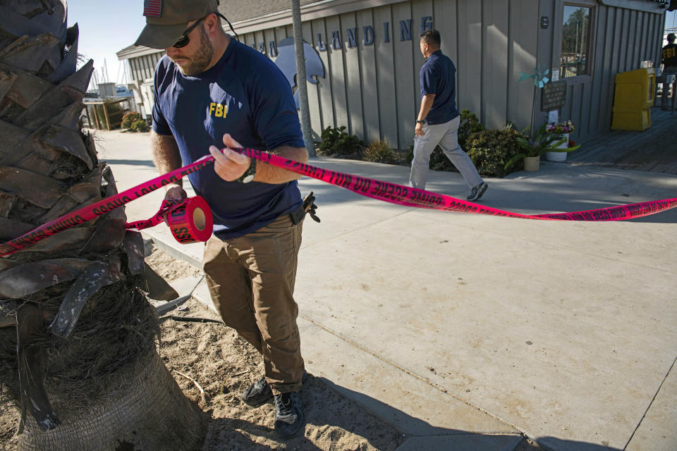 FILE - In this Sept. 8, 2019 file photo, FBI agents set a perimeter around the Truth Aquatics office, the California company that owned the scuba diving boat that caught fire and killed 34 people last week, as authorities issue a search warrant for the company and the sister vessels of the Conception dive boat on the Santa Barbara Harbor in Santa Barbara, Calif. Authorities conducting a criminal investigation into the deadly scuba diving boat fire plan to interview previous patrons of the boat company to determine what kind of safety information they were provided during trips, a law enforcement source said. (AP Photo/Christian Monterrosa, File)