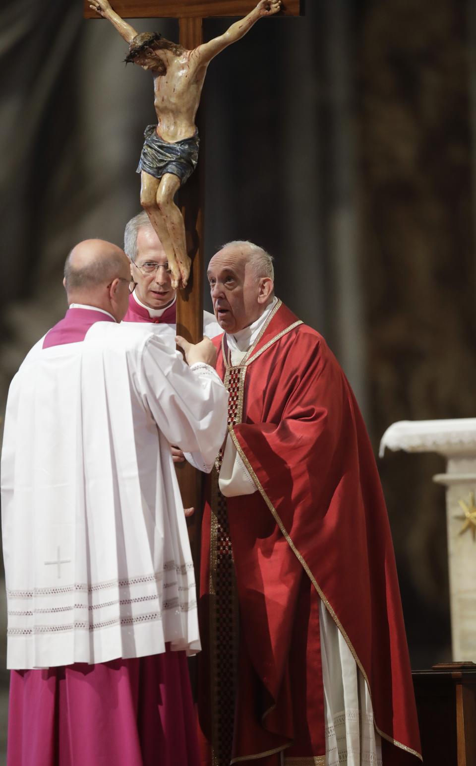 Pope Francis holds a crucifix as he celebrates Mass for the Passion of Christ, in St. Peter's Basilica, at the Vatican, Friday, April 19, 2019. Pope Francis began the Good Friday service at the Vatican with the Passion of Christ Mass and hours later will go to the ancient Colosseum in Rome for the traditional Way of the Cross procession. (AP Photo/Alessandra Tarantino)