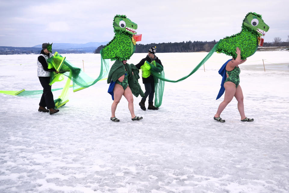 Two swimmers, dressed as the Memphre the Lake Monster, walk across the ice following their lap at the 25 meter hat competition during the winter swimming festival on frozen Lake Memphremagog, Friday, Feb. 23, 2024, in Newport, Vermont. (AP Photo/Charles Krupa)