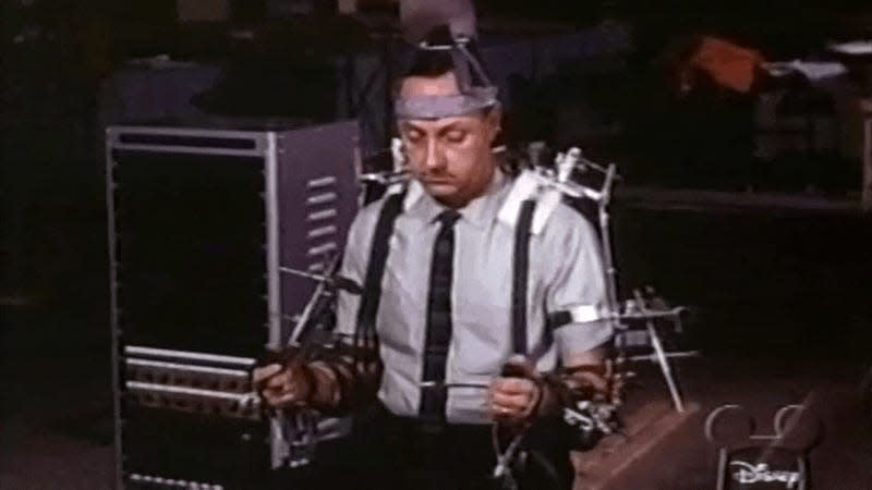 A robot from the 1964 World’s Fair attraction Carousel of Progress is demonstrated by Walt Disney and an engineer using a waldo-style manipulation device.<br> - Gif: Disney