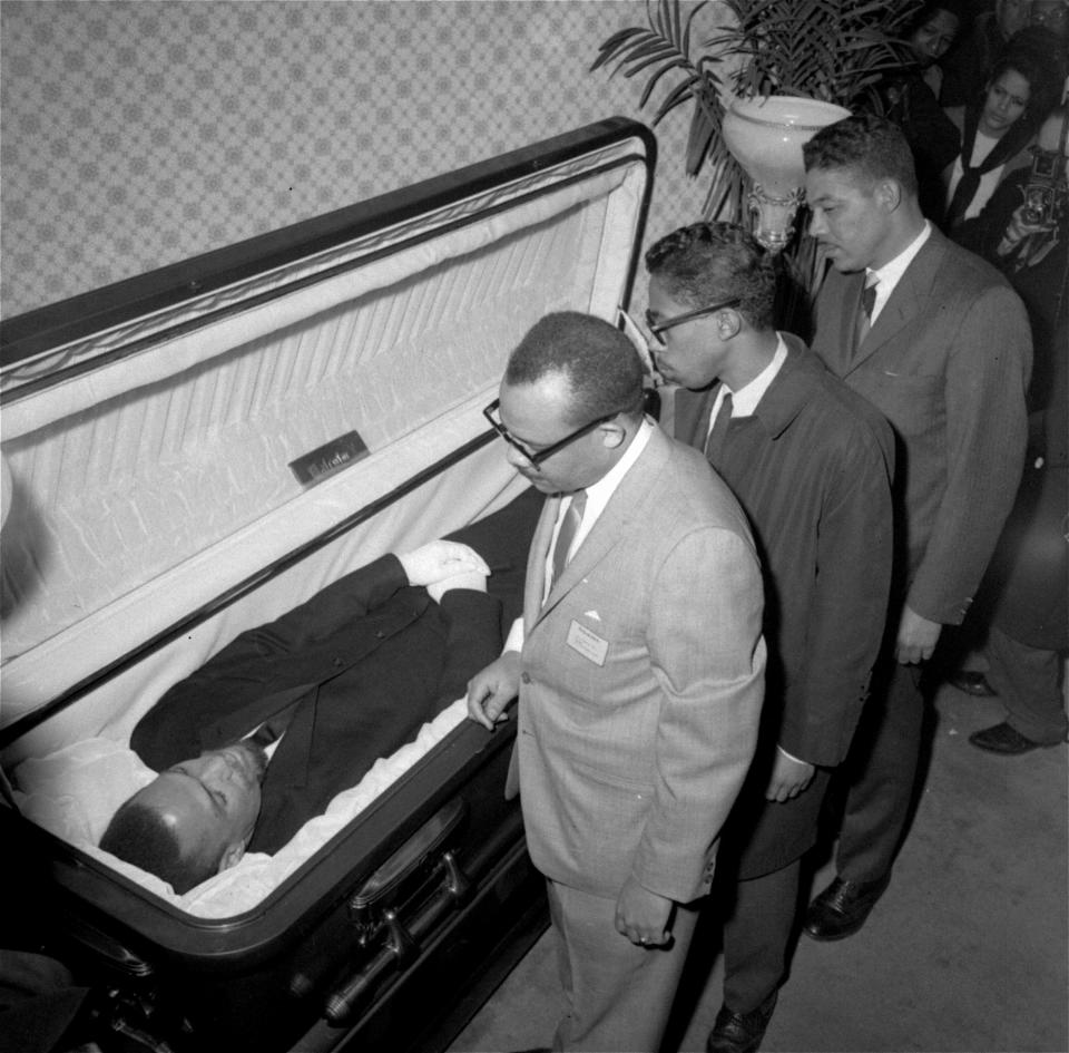 File - In this Feb. 24, 1965, file photo, the body of Malcolm X, black nationalist leader who was slain February 21, 1965, at a rally of his organization, is viewed by newsmen at the Unity Funeral Home, Eighth Avenue and 126th Street in New York City. "Who Killed Malcolm X?" currently streaming on Netflix dives into questions surrounding his assassination and allegations of a botched investigation. (AP Photo/File)