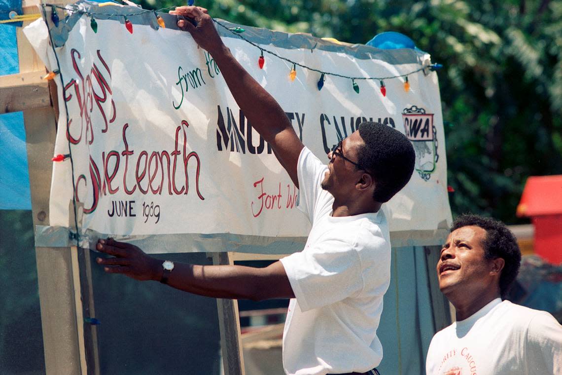 Clarence Walker, left, tapes up a sign at a Juneteenth celebration in 1989 that drew hundreds in Fort Worth. Looking on is Glen Holt.