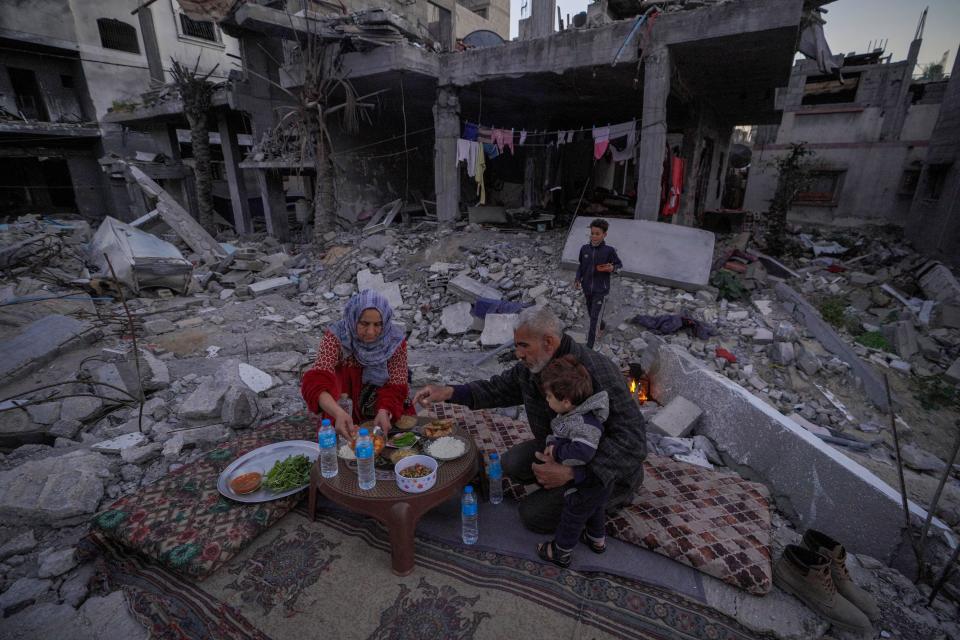 The Palestinian Al-Naji family prepare to break their fast during the first day of the Muslim holy fasting month of Ramadan sitting amid the ruins of their family house in Deir el-Balah, central Gaza Strip, on March 11, 2024, amid ongoing battles between Israel and the militant group Hamas.