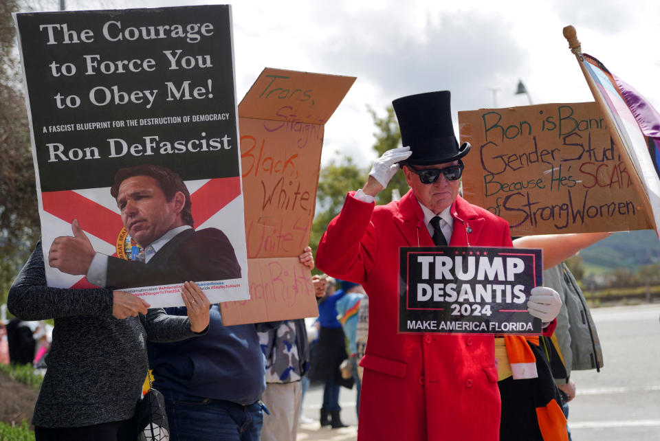 A man holds a sign supporting Florida Governor and likely 2024 Republican presidential candidate Ron DeSantis and former U.S. President Donald Trump as people gather and protest against DeSantis speaking at the Ronald Reagan Presidential Library in Simi Valley, California, U.S. March 5, 2023. REUTERS/Allison Dinner