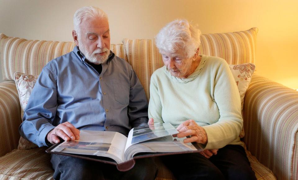 Ellen Dunne looks over family photos with her son Jack, of East Bridgewater, one of her nine children. She lives in Hanover and will turn 100 on St. Patrick's Day.