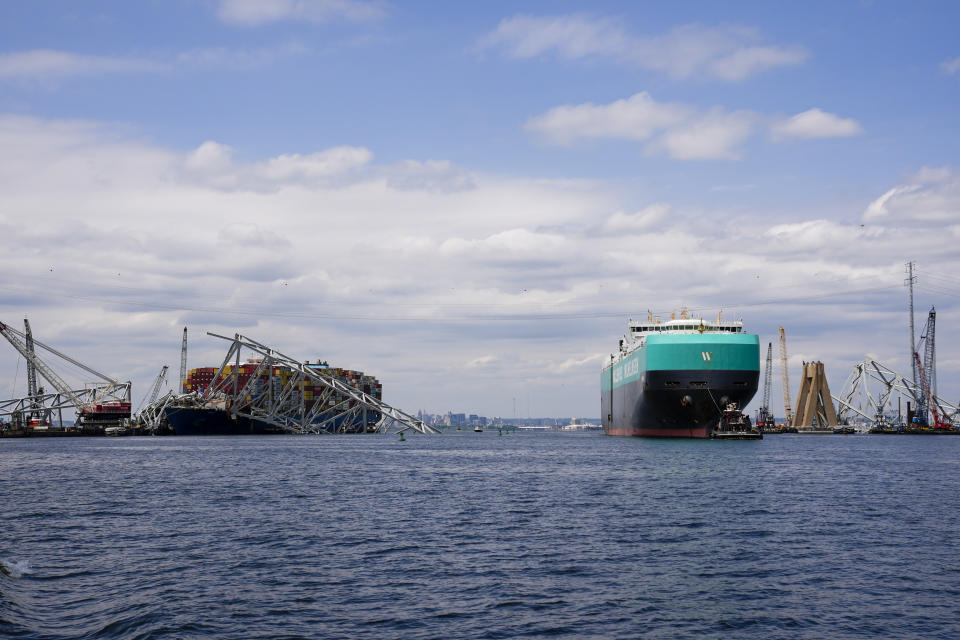 A vessel, right, moves past the stranded container ship Dali, through a newly opened deep-water channel in Baltimore after being stuck in the harbor since the Francis Scott Key Bridge collapsed four weeks ago, Thursday, April 25, 2024. (AP Photo/Matt Rourke)