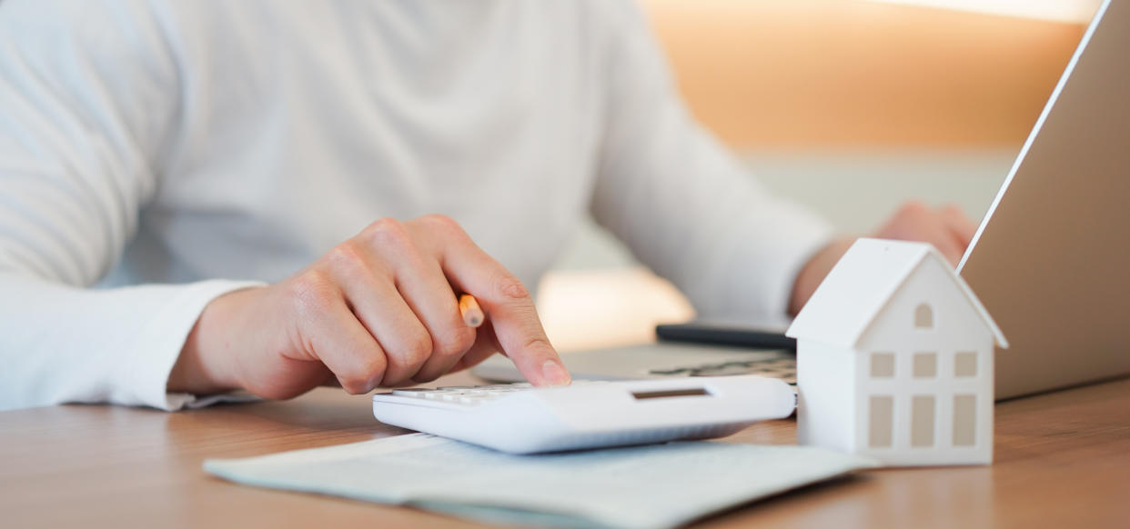 close up young man hand press on calculator to check and summary expense of home loan mortgage for refinance plan , people lifestyle concept