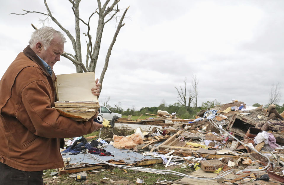 Robert Scott looks through a family Bible that he pulled out of the rubble Sunday, April 14, 2019, from his Seely Drive home outside of Hamilton, Miss., after an apparent tornado touched down Saturday night. (AP Photo/Jim Lytle)