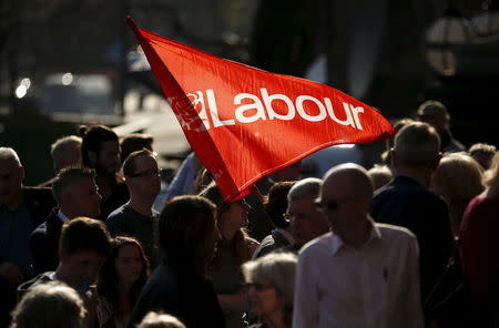 Supporters wave a flag as they wait to listen to Britain's opposition Labour Party leader Ed Miliband at a speech on health at a campaign event in Leeds, northern England, April 23, 2015. REUTERS/Phil Noble