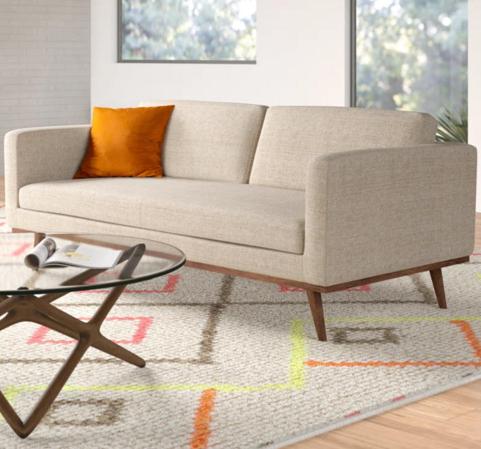 beige upholstered sofa with wooden base and legs