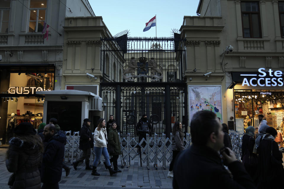 People pass by the guarded entrance of the Consulate General of the Netherlands, in Istanbul, Thursday, Feb. 2, 2023. Turkey on Thursday slammed a group of Western countries that temporarily closed down their consulates in Istanbul over security concerns, accusing them of waging “psychological warfare” and attempting to wreck Turkey’s tourism industry. (AP Photo/Khalil Hamra)