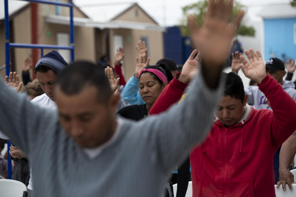 In this Oct. 12, 2019 photo, Cubans pray at a migrant shelter in Reynosa, Mexico. In years past, migrants seeking asylum in the United States moved quickly through this violent territory on their way to the U.S., but now due to Trump administration policies, they remain here for weeks and sometimes months as they await their U.S. court dates, often in the hands of gangsters who hold Tamaulipas state in a vice-like grip. (AP Photo/Fernando Llano)